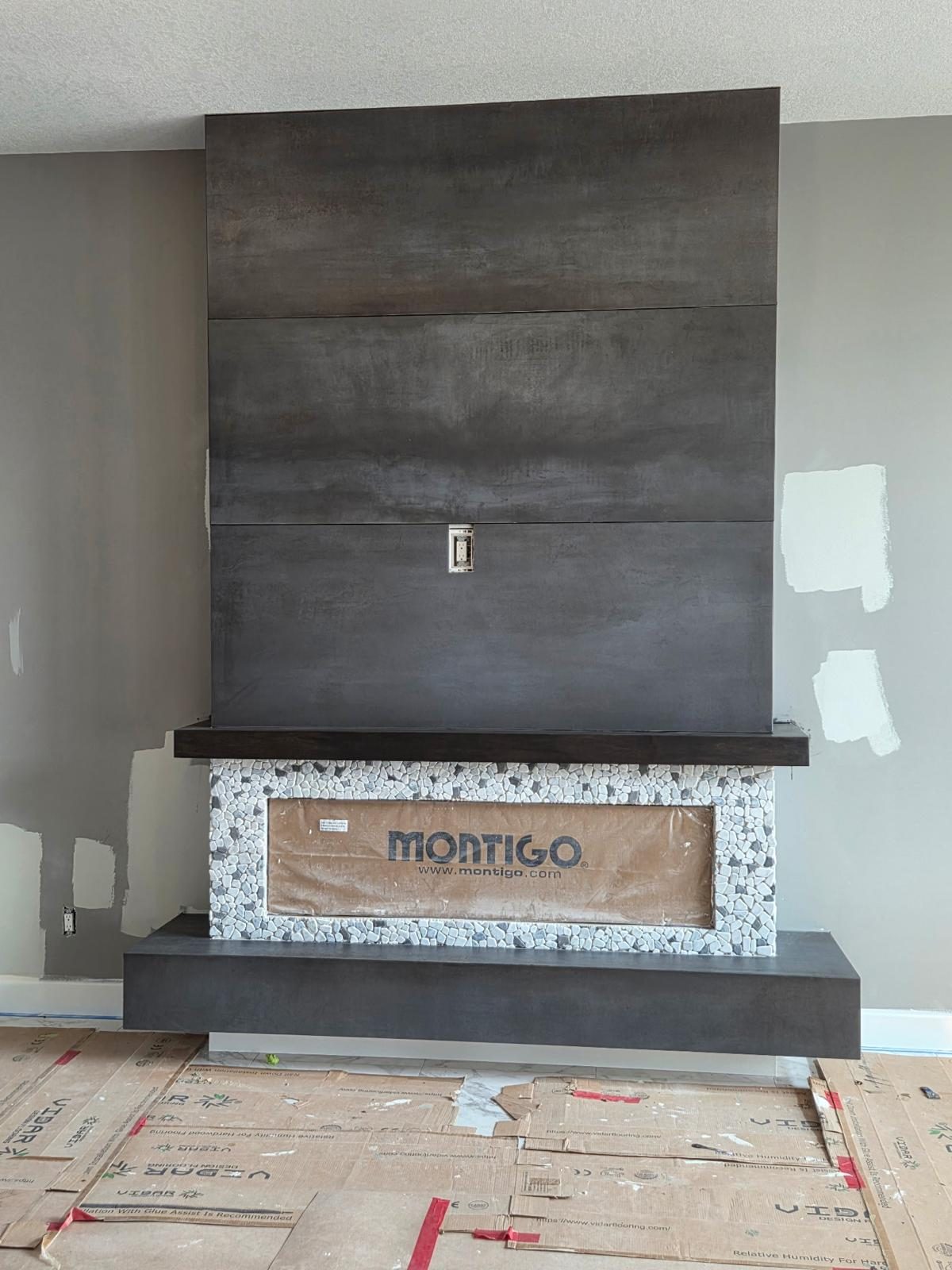 Fireplace wall clad in large-format porcelain slab with a pebble mosaic surround and floating mantel